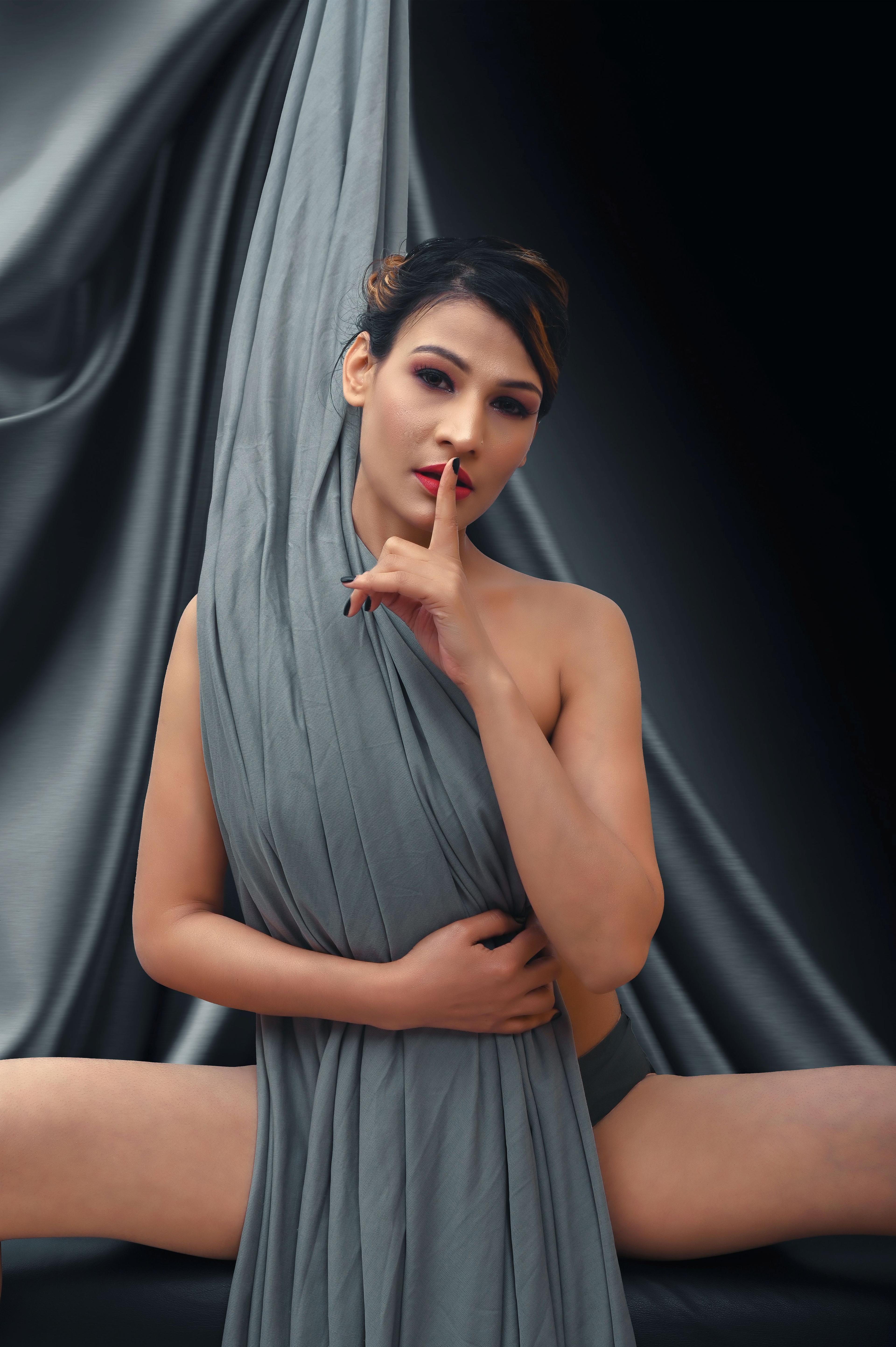 Woman draped in gray fabric with finger to lips, illustrating a Cape Town escort guide